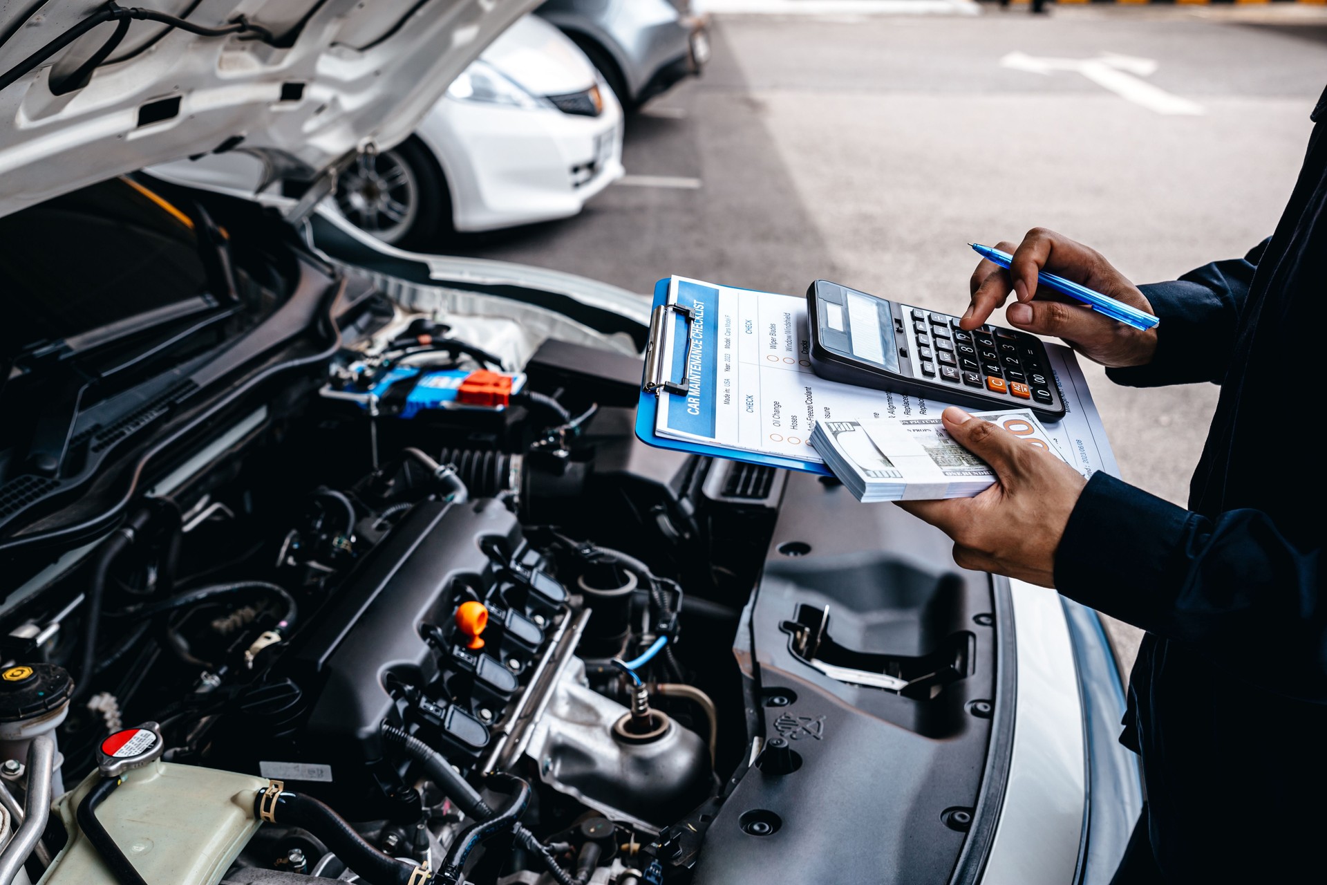 Mechanic calculates the cost of car repairs to customer at garage workshop.