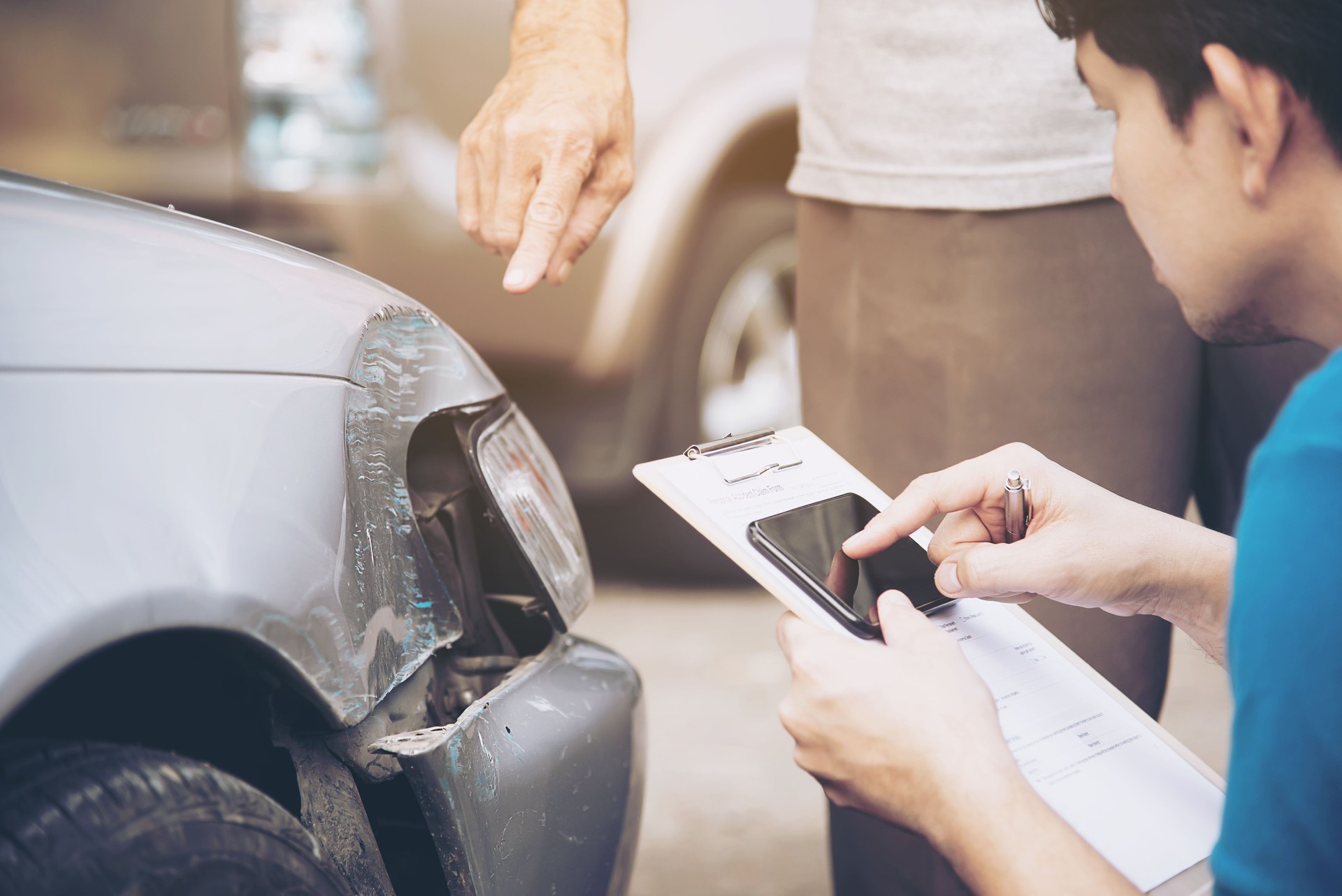 Man Holding Mobile Phone And Paper By Customer Showing Damaged Car